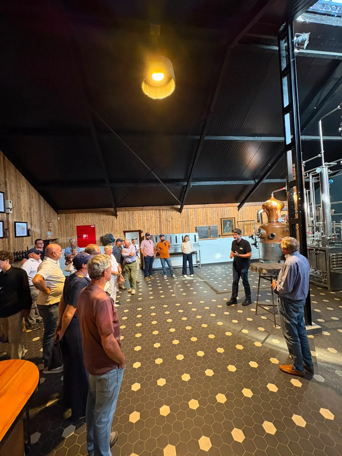 Deelnemers luisteren naar een rondleiding tussen de distilleerketels